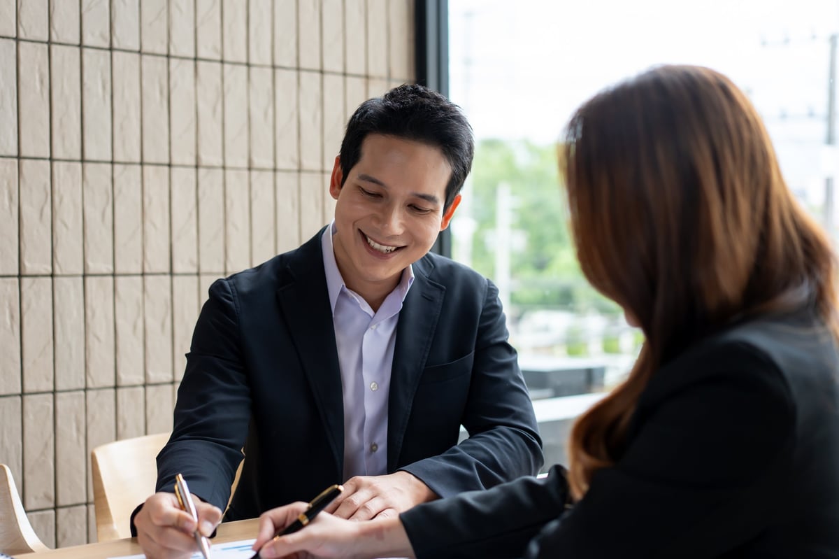 A smiling property owner reviewing closing papers during a real estate transaction